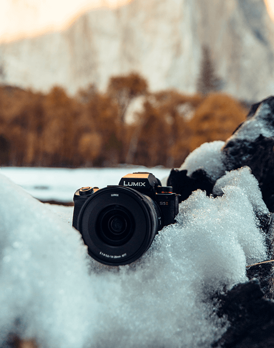 Panasonic Lumix S5 Mark II avec objectif posé dans la neige avec montagne en fond